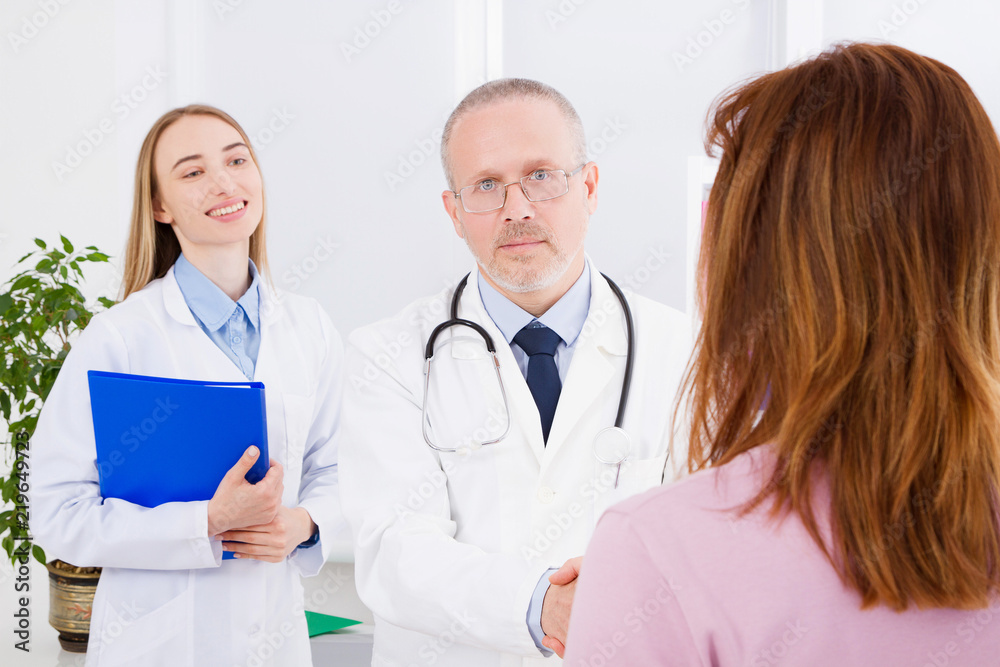 Doctor is talking with woman patient and sitting in medical office.Man in white uniform. Medical insurance. Copy space. Quality medicine concept. Doctor is talking with woman patient and sitting in medical office.Man in white uniform. Medical insurance. Copy space. Quality medicine concept.