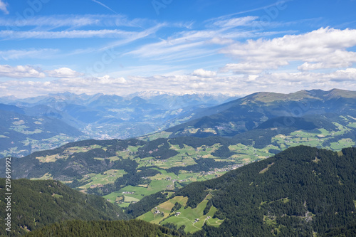 Aerial view of an Alp valley with fields and farms and mountain peaks