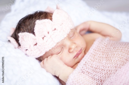 Sweet sleeping tiny newborn princess with a pink crown wrapped in a soft blanket. Cute newborn baby sleeping stock image.