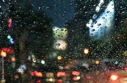 Raindrops on the car windshield with blurred traffic jam on the urban street at night 
