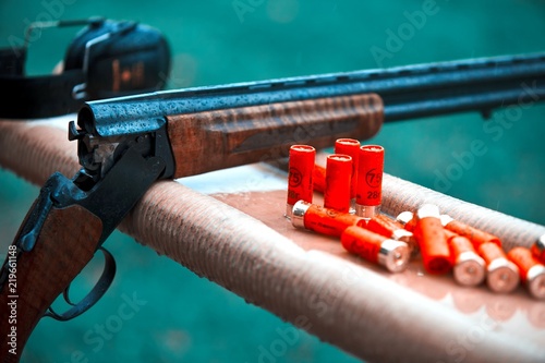 Hunting shotgun with bullets cartridges drop rain. smoke