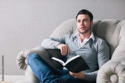 Handsome man sitting in an armchair and thinking