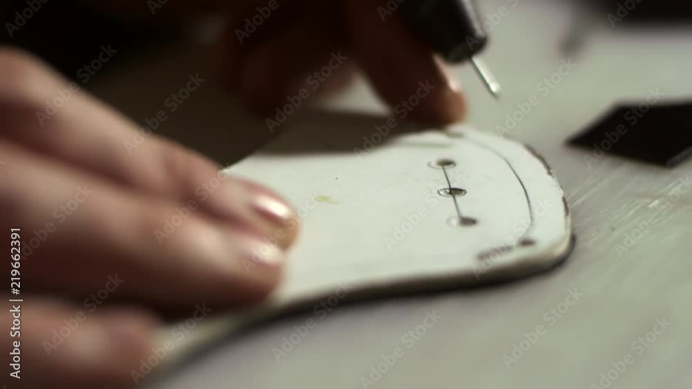 Handmade tailoring in shoes production. Close up leather craftsman hands working with leather sketch. Artisan man making holes in leather blank with awl. Design process leather goods in industry Handmade tailoring in shoes production. Close up leather craftsman hands working with leather sketch. Artisan man making holes in leather blank with awl. Design process leather goods in industry