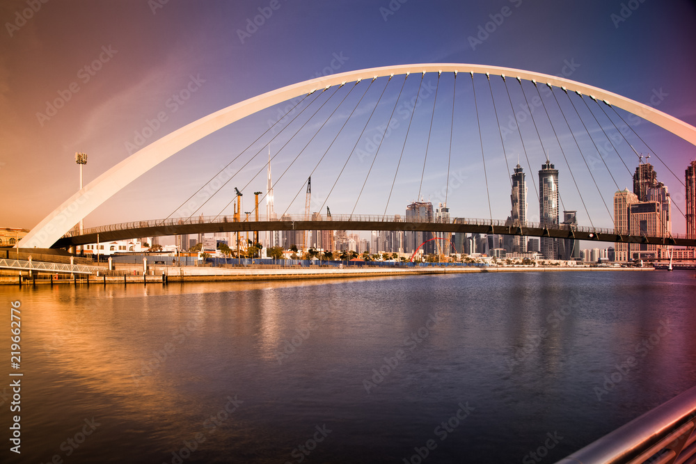 Naklejka premium DUBAI, UAE - FEBRUARY 2018: Colorful sunset over Dubai Downtown skyscrapers and the newly built Tolerance bridge as viewed from the Dubai water canal.
