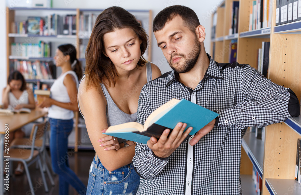Young people choosing books in library