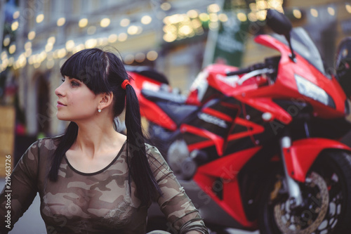 happy woman biker sitting near motorcycle and happy, close-up brunette with red bike