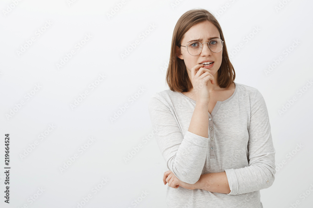 Waist-up shot of concerned troubled cute european female in glasses and blouse holding finger on lip frowning looking nervous and worried waiting for news from hospital holding hand crossed on body Waist-up shot of concerned troubled cute european female in glasses and blouse holding finger on lip frowning looking nervous and worried waiting for news from hospital holding hand crossed on body