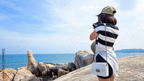 Young woman are using a DSLR camera to photography of the Hin Ta Hin Yai and beautiful nature landscape of blue sea and sky during summer travel at Koh Samui island, Surat Thani, Thailan photo