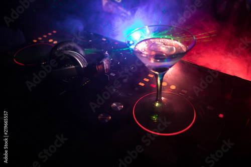 Photo Glass with martini with olive inside on dj controller in night club