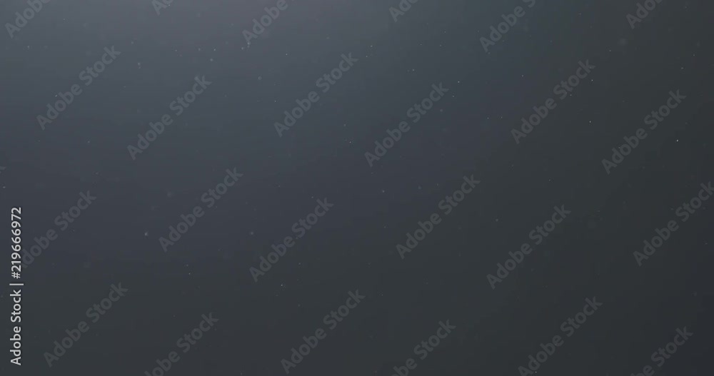 Slow motion backlit dust particles floating in the air on a black background Slow motion backlit dust particles floating in the air on a black background
