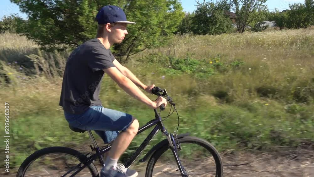 Handsome teenager boy riding bike on summer road Handsome teenager boy riding bike on summer road