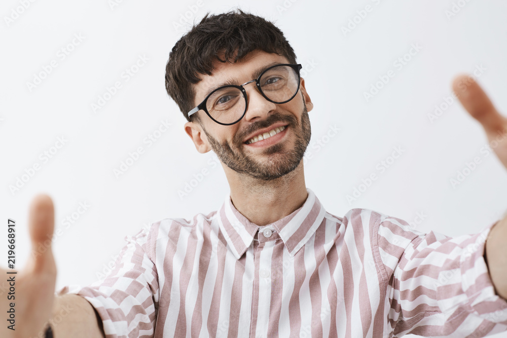 Headshot of pleased and cute good-looking happy caucasian bearded guy with  stylish hairstyle in cool trendy striped shirt pulling hands towads camera  as if taking selfie smiling joyfully Stock Photo | Adobe