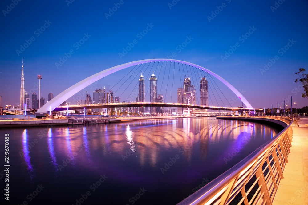 Fototapeta premium Dubaj, Zjednoczone Emiraty Arabskie - luty 2018: Kolorowy zachód słońca nad drapaczami chmur w centrum Dubaju i nowo wybudowanym mostem tolerancji, patrząc z kanału wodnego w Dubaju.