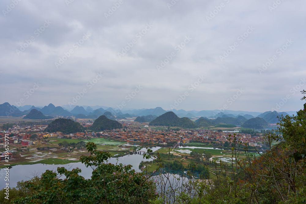 Village between mountain range from viewpoint of peak mountain in cloudy day at Puzhehei, Yunnan, China.