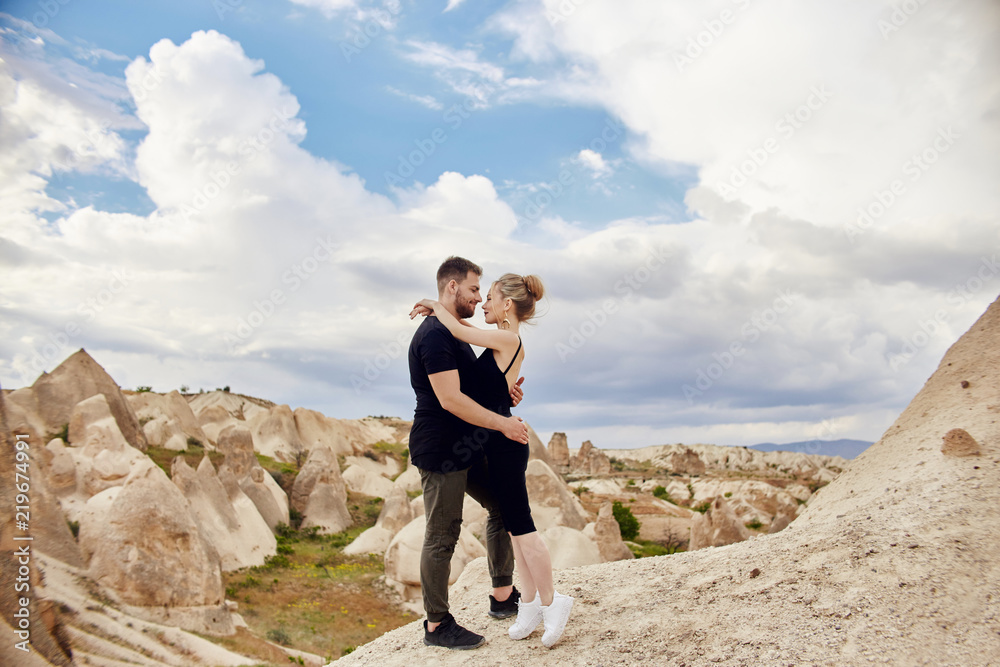 Fashion East couple hugging with mountains in background. Man and woman loving relationship. Beautiful mountains of Cappadocia, Turkey are incredible