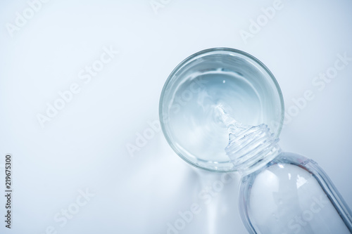 pouring water from bottle into glass on white background