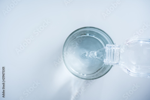 pouring water from bottle into glass on white background