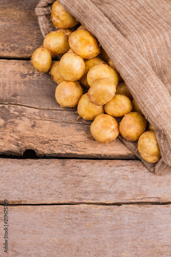 Young potatoes in a sack close up. Wooden desk background.