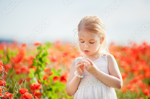 Little blonde girl in the poppy field