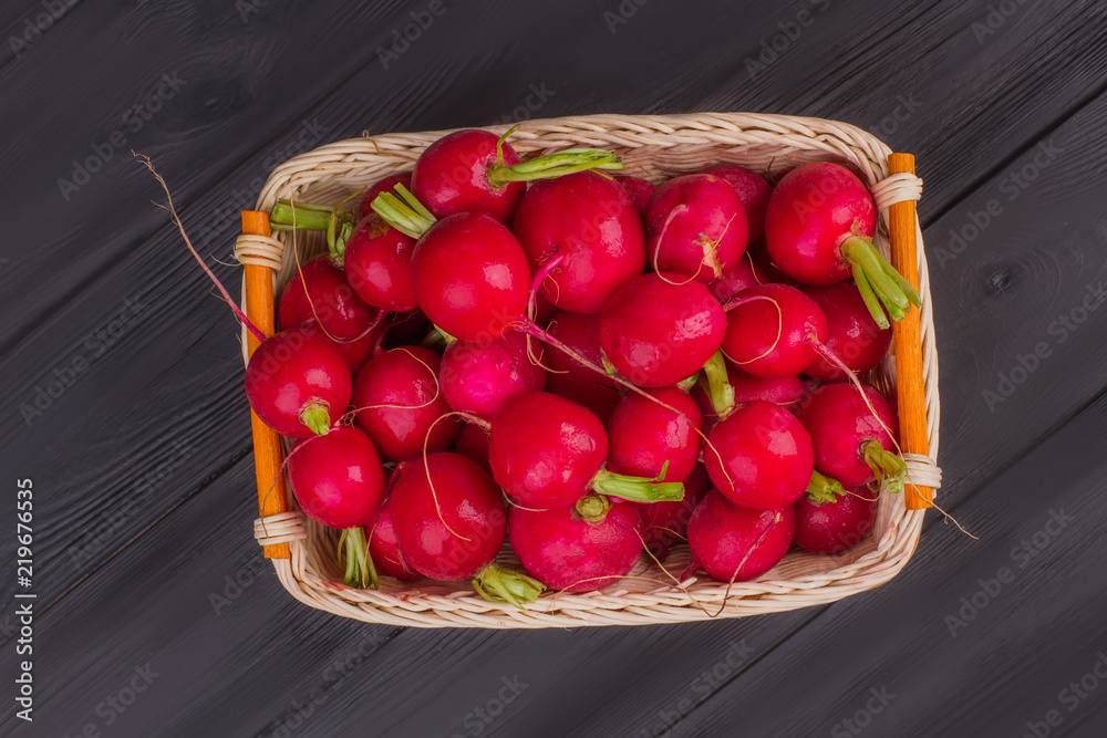 Pile of many radishes in wicked basket. Dark wooden table background. Pile of many radishes in wicked basket. Dark wooden table background.