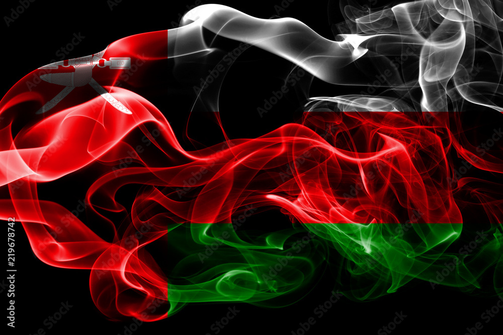 Fototapeta premium National flag of Oman made from colored smoke isolated on black background. Abstract silky wave background.