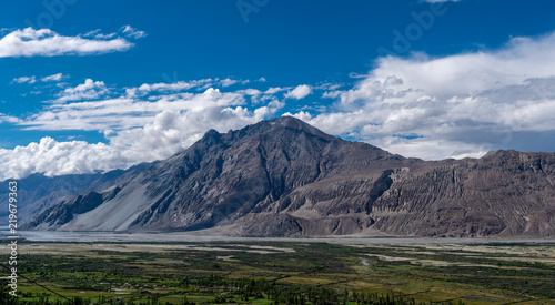 Diskit Gompa and Sand Dune of Nubra Valley with mountains in background and cloudy blue sky in summer of Leh Ladakh, Jammu and Kashmir, India