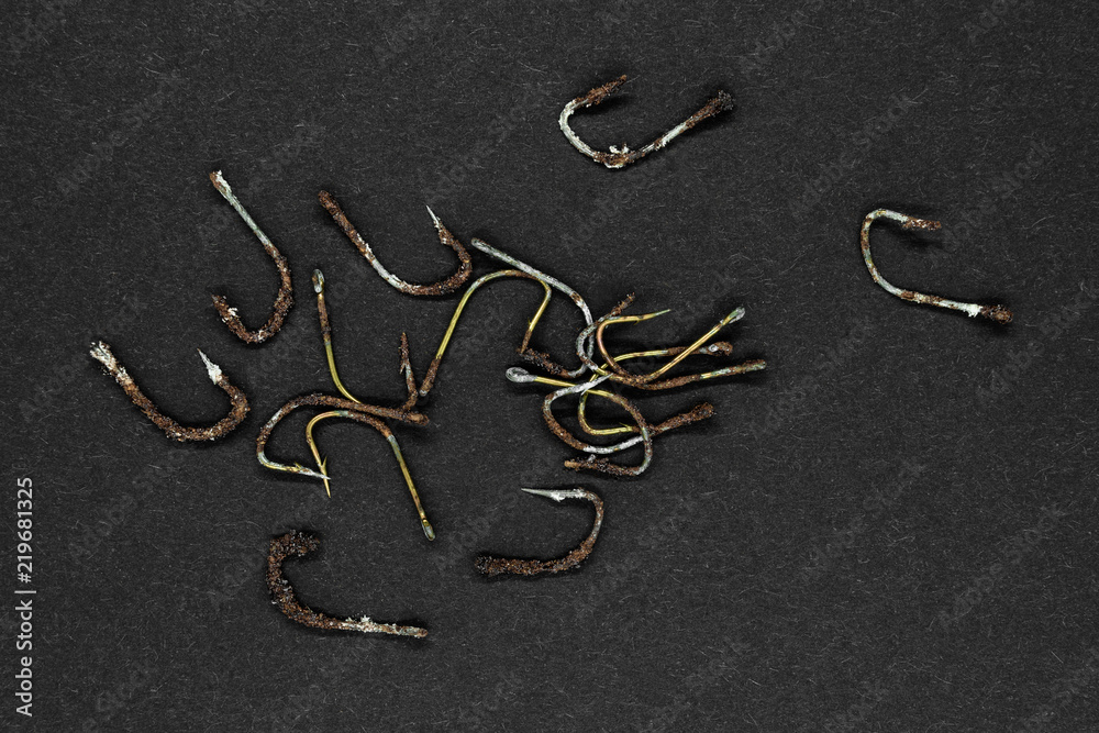 Bunch of very old and rusty fishing hooks on black background surface Bunch of very old and rusty fishing hooks on black background surface