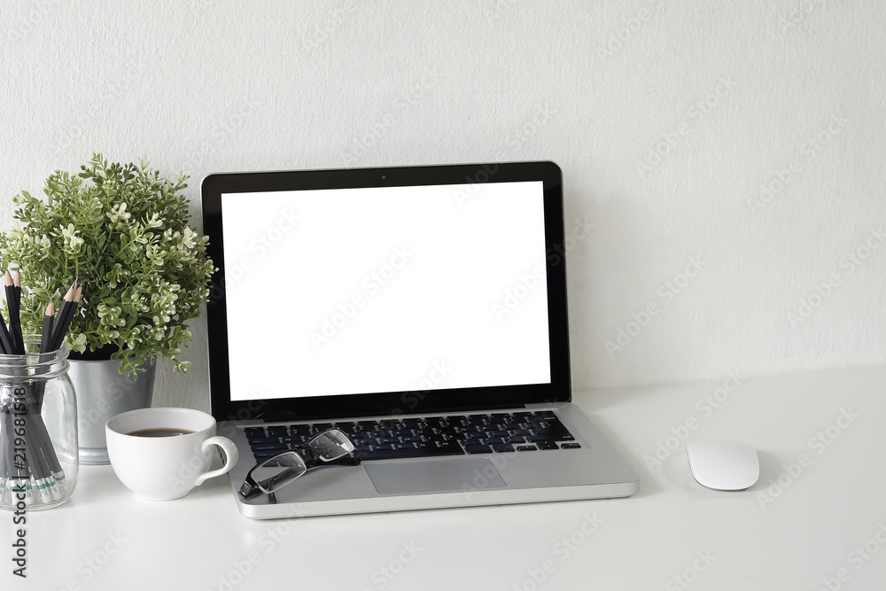 Fototapeta premium Workspace Mock up laptop computer on white table with mug of coffee, plat in pot and notebook paper copy space office table.