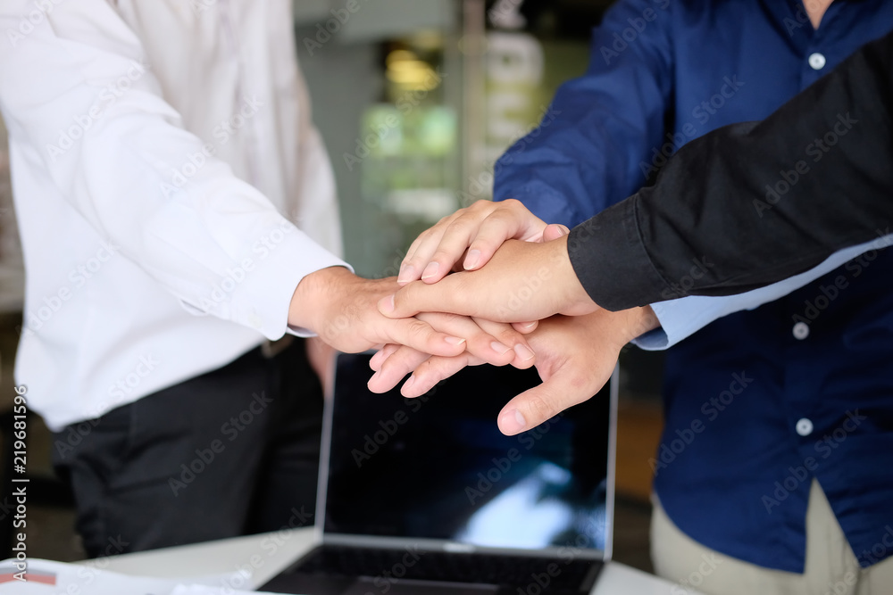 Obraz premium Close up young business people putting their hands together. Stack of hands on office workplace. Unity and teamwork concept.