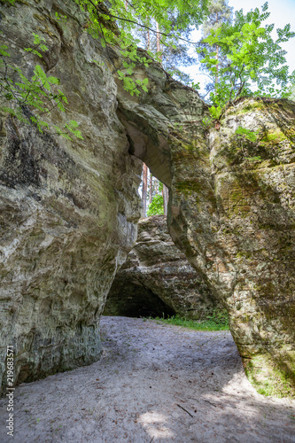 Scenic view to the picturesque sandstone caves Liela Ellite eroded by water in sunny autumn morning with fallen leaves on the ground in Liepas parish, Priekulu district, Vidzeme region, Latvia