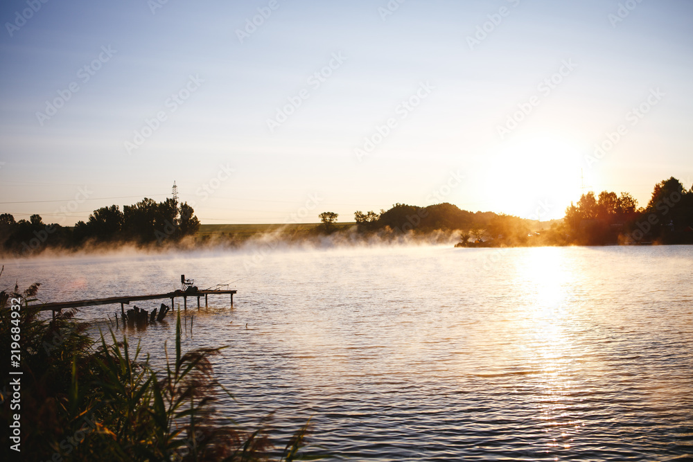 Fishing equipment on seat on lake. Feeder carp rods on wooden pier