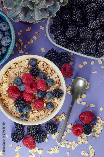 Healthy breakfast. White plate with oatmeal strewn and different berries on a blue background. photo