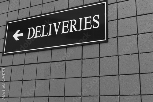 Deliveries sign on side of building in black and white