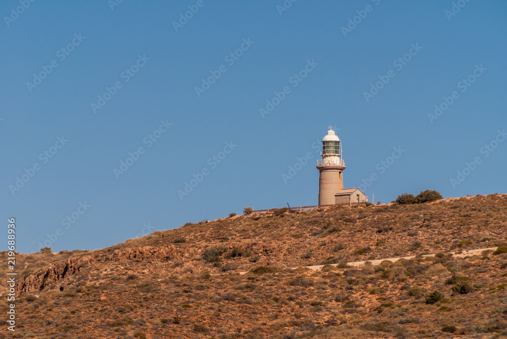 Exmouth, Western Australia - November 27, 2009: Long shot on Vlaming Head Lighthouse On brown rocky hill against deep blue sky. 
