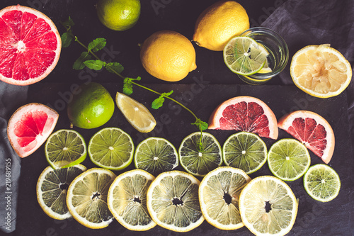 Citrus fruits: lemons, grapefruits and limes sliced, top view flat lay. Dark background