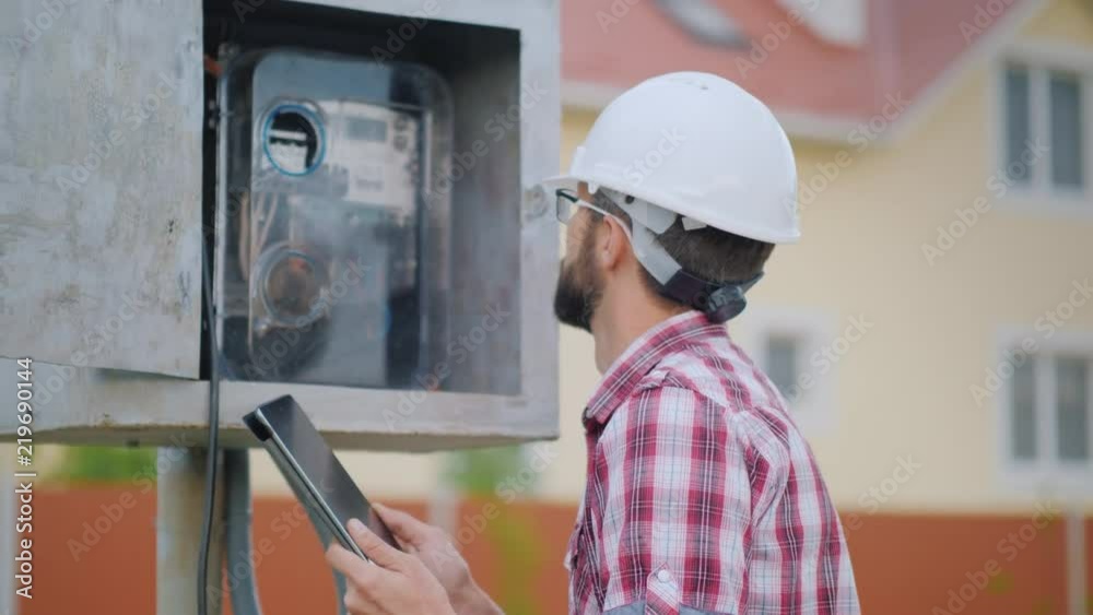 The man inspector records the meter readings. On the background of private cottages