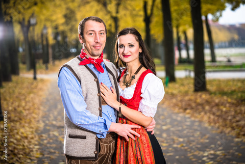 Bavarin Germans in Dirndl and Lederhose, leant against each other photo