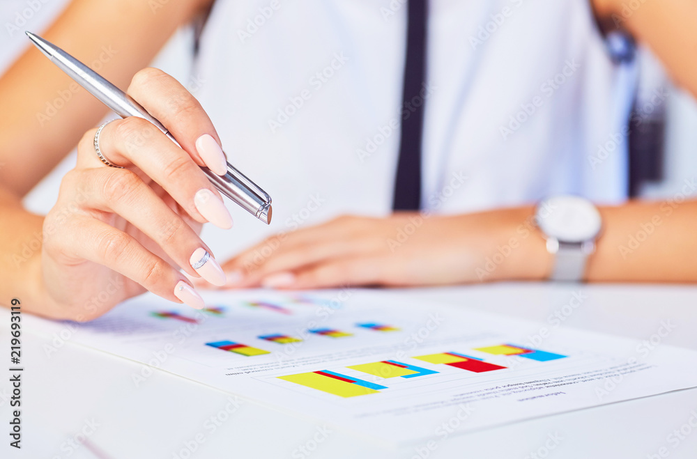 Female hand point silver pen to business graph on seminar. Bank credit, loan money, invest, tax situation review, income calculation form concept.