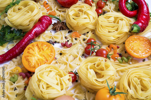 Italian pasta of various kinds with spices, red hot pepper, chicken eggs on a white background