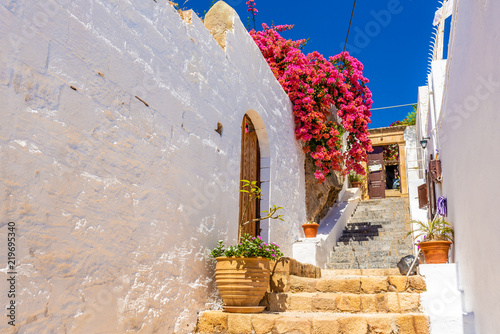 Beautiful Greek street with summer flowers in Lindos village. Rhodes island. Greece.