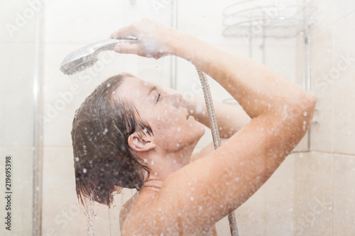 The young woman uses a shower in the bathroom of her house
