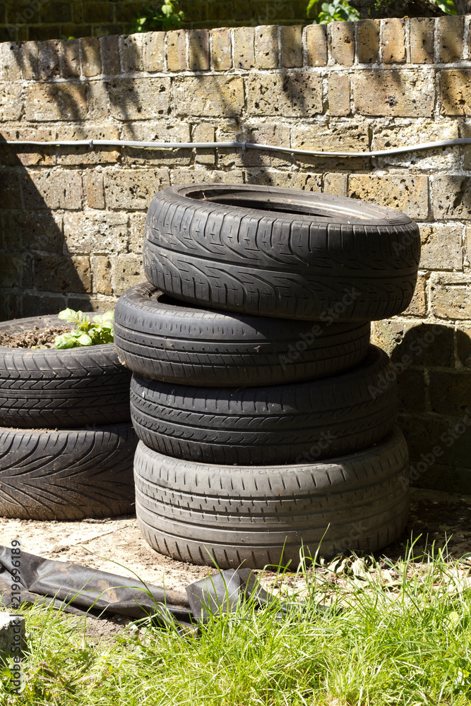 Fototapeta premium Stack of used tyres being used a plant pot