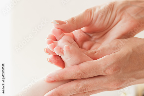 Hands of woman holds baby foot