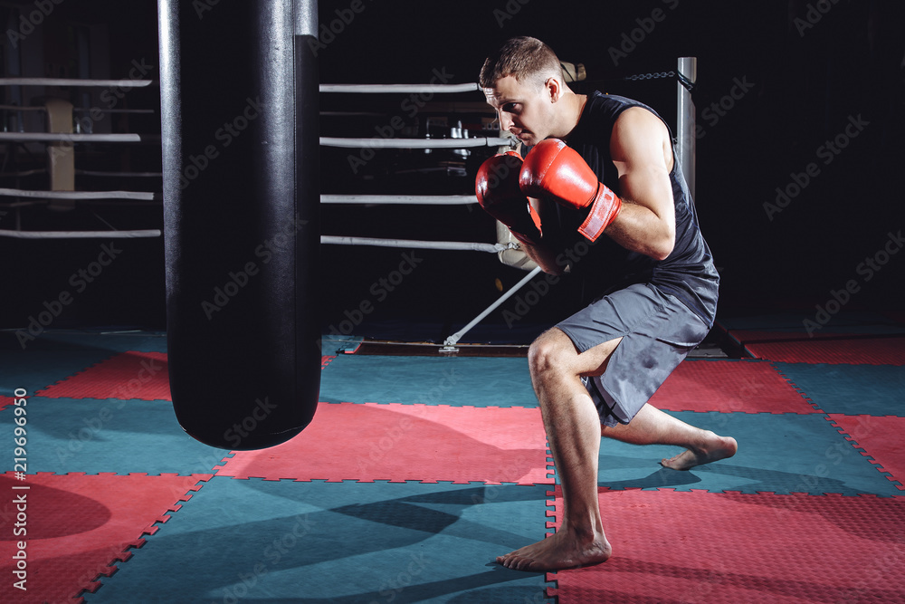 Photo of young strong sports man boxer make exercises in gym.
