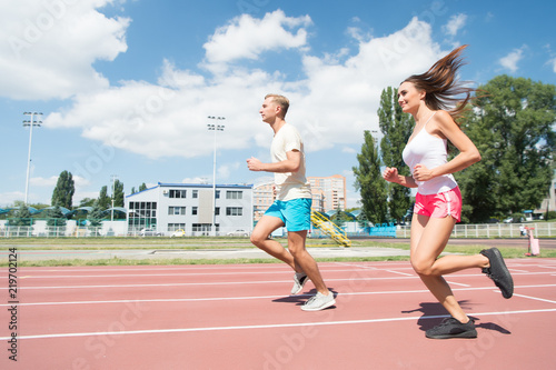Young family promoting healthy lifestyle. Woman and man run stadium. Coach and sportsman motion run training before race. Couple runners training outdoors. Couple or family live healthy lifestyle