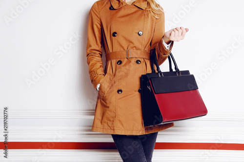 Trendy woman with black and red bag in hand. Autumn outfit
