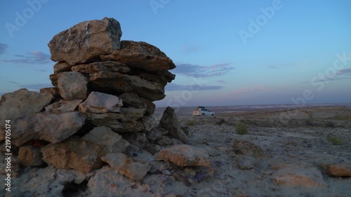 cars drive through the desert past the stones