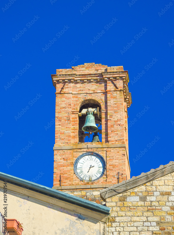tower with bells of the ancient village of medieval origin in the blue sky
