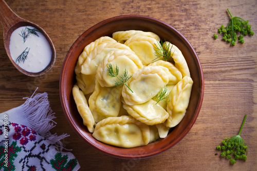 Dumplings, filled with cheese - vegetarian dish. Varenyky, vareniki, pierogi, pyrohy in a bowl on wooden table. overhead, horizontal