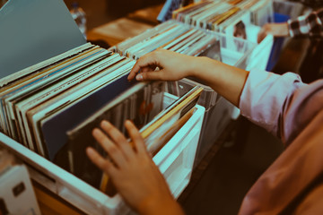 Fotobehang Muziekwinkel Vrouw kiest vinylplaat in platenzaak  © Ivan Kurmyshov